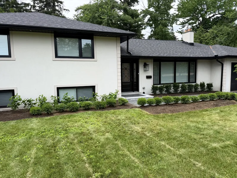 Newly laid lawn running up to the house, roller stripes still visible across the grade.