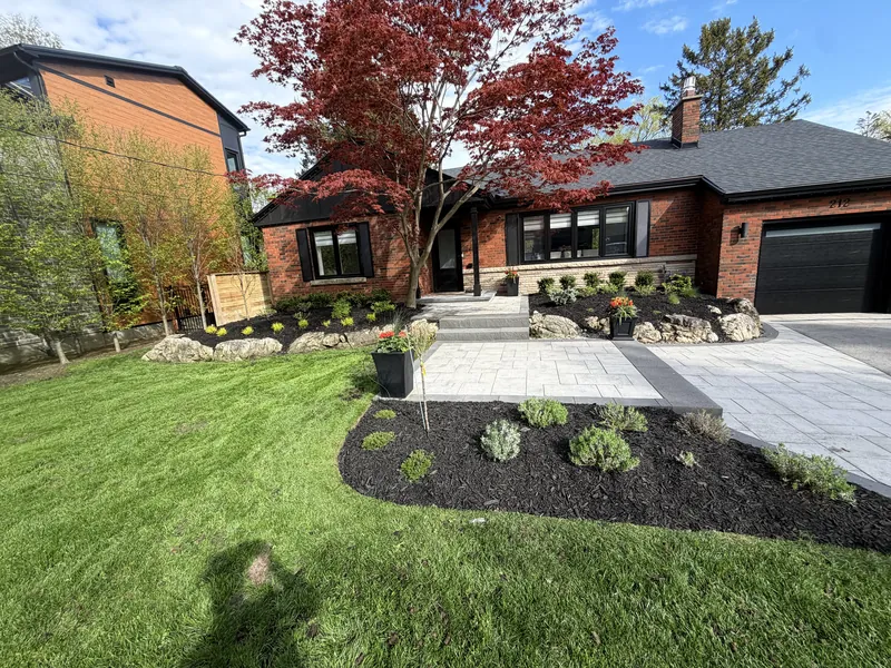 Front entrance rebuilt in grey pavers with a charcoal border, boulder-set beds and a Japanese maple by the door.